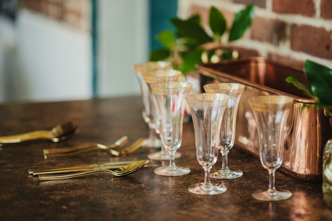 Äldre dekorativa glas och guldfärgat bestick på ett mörkt bord